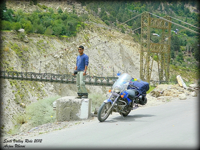 bridge amonst roacks and an indian rider with his bajaj avenger